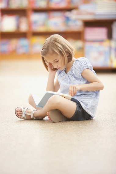Petite fille assise, qui lit un livre